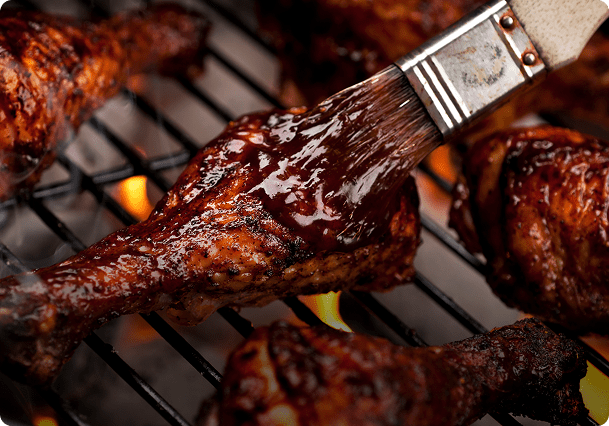 Grilled chicken with barbecue sauce on grill.
