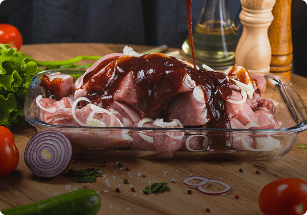 Raw meat with onions and sauce in dish.